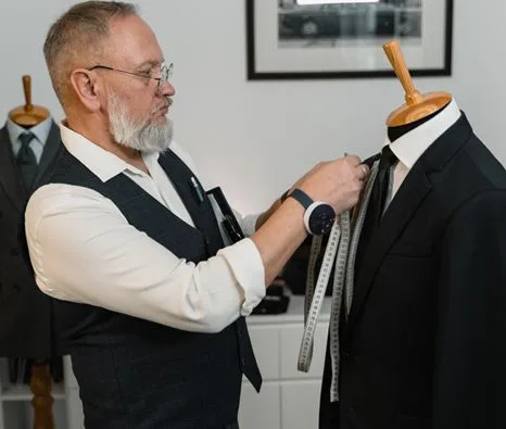 Tailor measuring suit on mannequin with measuring tape in workshop