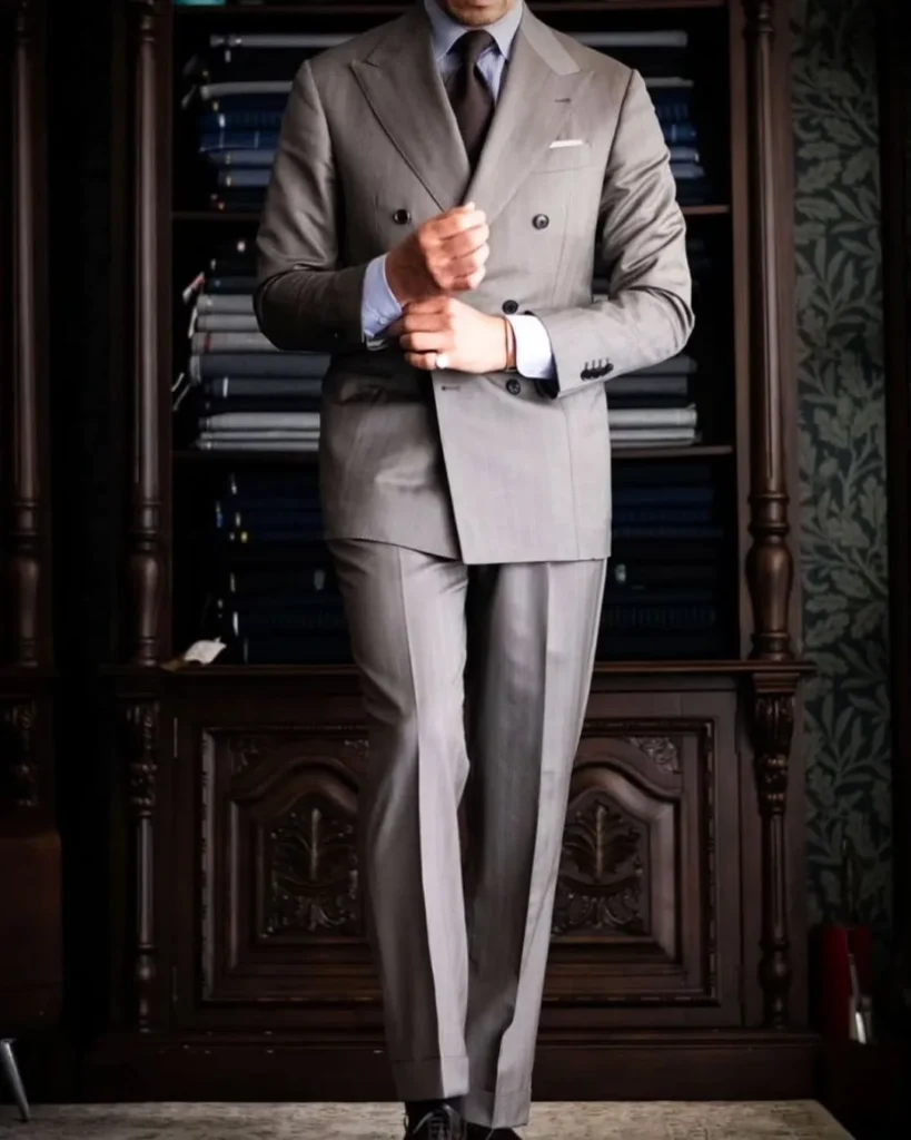 A man showcasing a grey double-breasted suit demonstrating how to make a suit look better.