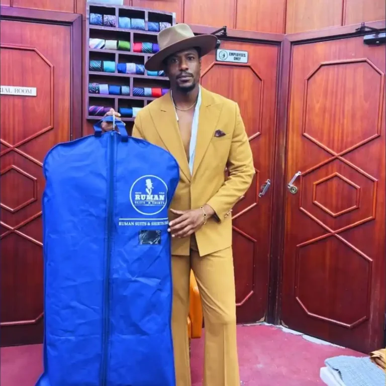 A gentleman in a mustard suit holding a Ruman Suits & Shirts garment bag, representing how to maintain and store your bespoke suit with professional care.