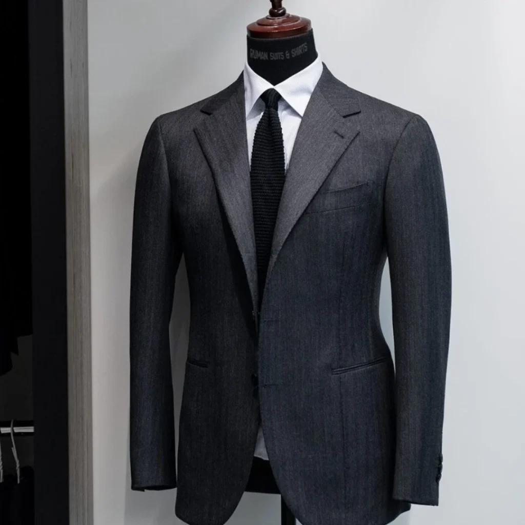 Must-Have Suits Every Man Should Own displayed with classic formal suits including navy, black, and grey styles arranged neatly.