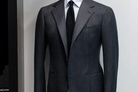 Must-Have Suits Every Man Should Own displayed with classic formal suits including navy, black, and grey styles arranged neatly.