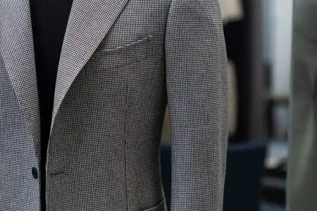 Tailor taking detailed measurements to explain what is a bespoke suit and how it is crafted from scratch.